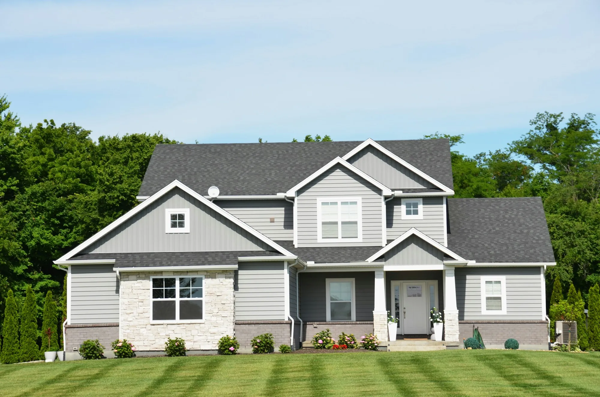Gray two-story suburban home with a striped green lawn