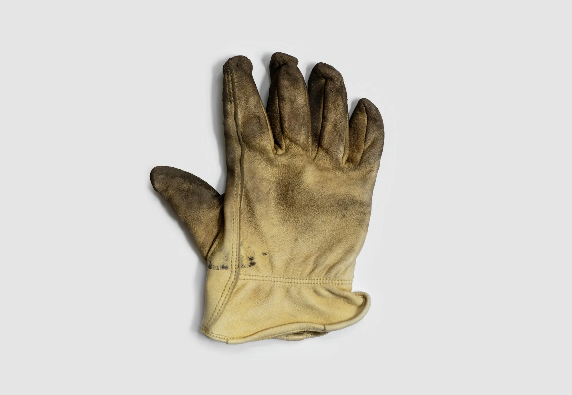 Worn leather work glove on a white background